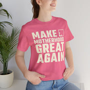 Image of smiling woman wearing pink color t shirt with saying "make motherhood great again" in white text with REDGlare arrow logo celebrating motherhood and not wokeness